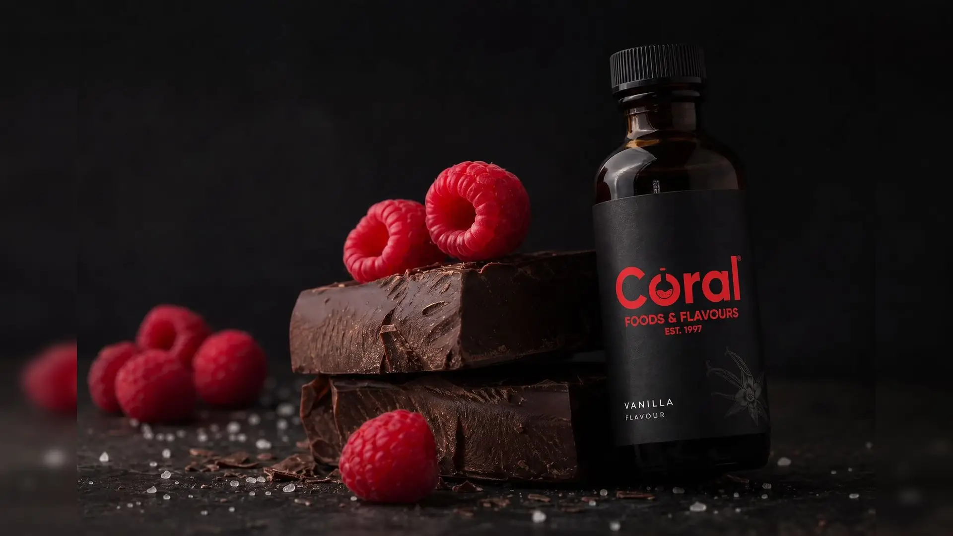 Coral vanilla flavour bottle beside dark chocolate and fresh raspberries